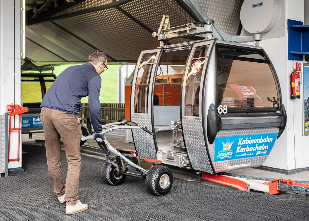 Valenta-Uphiller-012 Ein Mountaincart wird von einem Seilbahnmitarbeiter in eine Gondel geladen und wird mittels einer Transportvorrichtung von Valenta Metall fixiert und bergauf befördert.